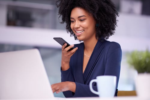 woman, in front of laptop, talking on a smartphone