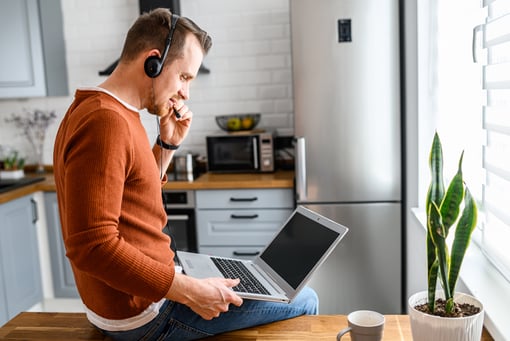 remote work man working in kitchen a man on his laptop taking a work phone call in his kitchen