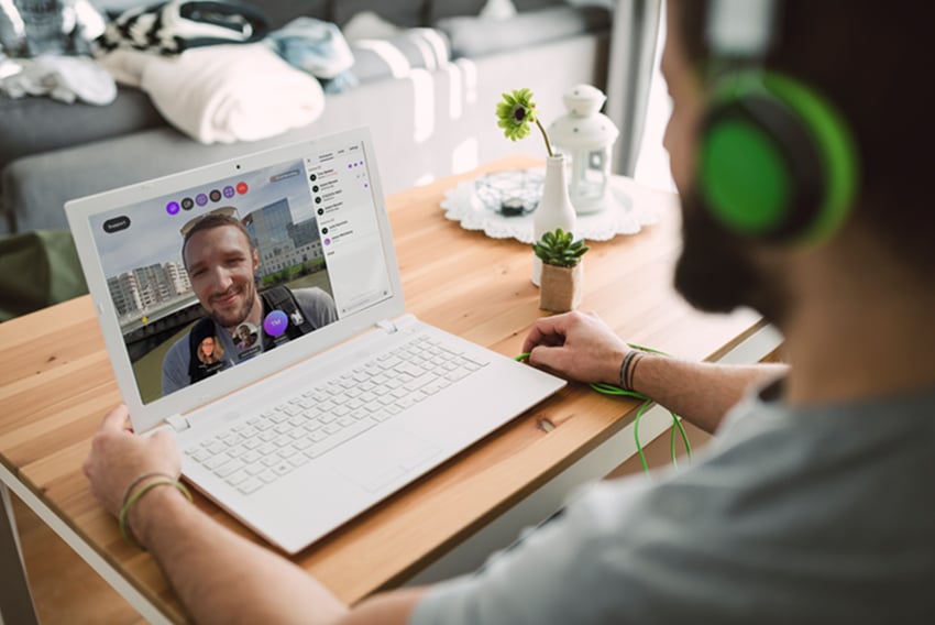 Video conferencing solutions help teams boost productivity and stay connected. Man video chatting on his laptop with another individual
