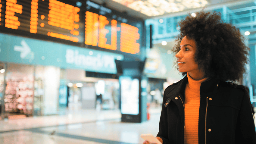 female traveler looking at flight board in an airport