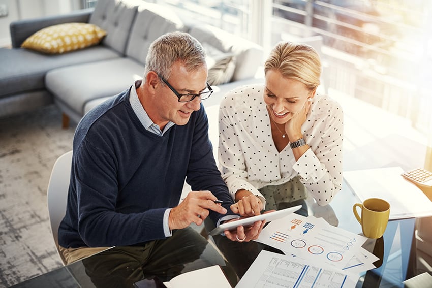 869595964 Shot of a mature couple using a digital tablet while going through paperwork at home
