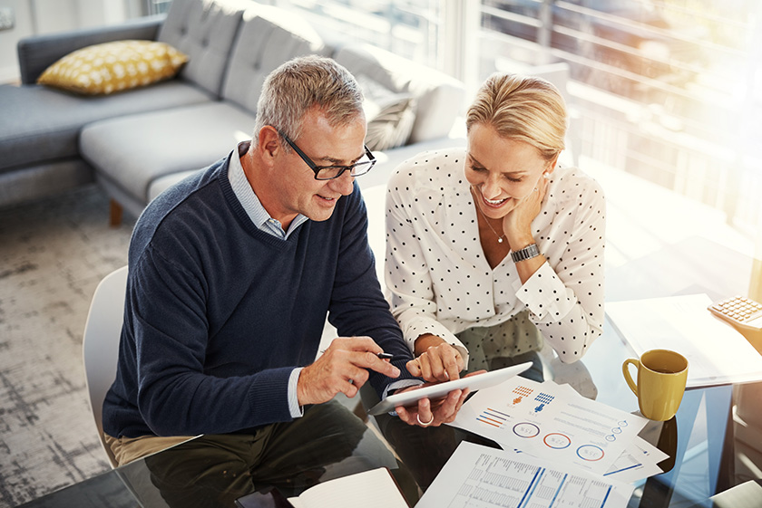 869595964 Shot of a mature couple using a digital tablet while going through paperwork at home